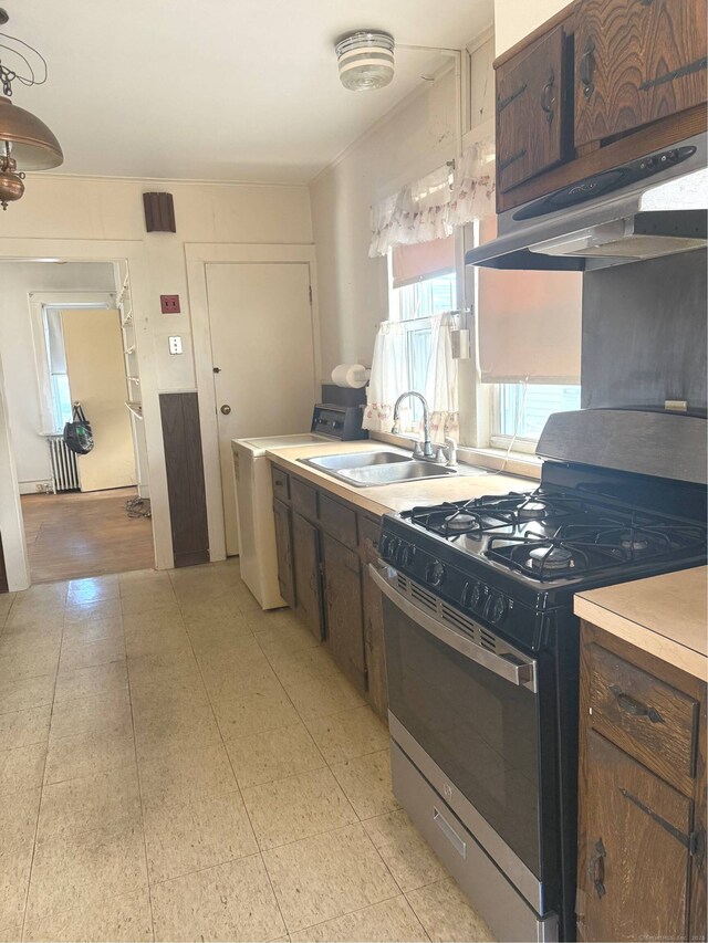 kitchen with gas range, washer / dryer, sink, and dark brown cabinets