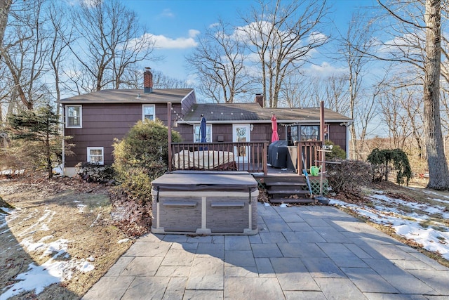 snow covered property featuring a garage, a hot tub, and a deck