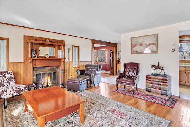 living room with crown molding, wooden walls, light hardwood / wood-style floors, and a baseboard heating unit