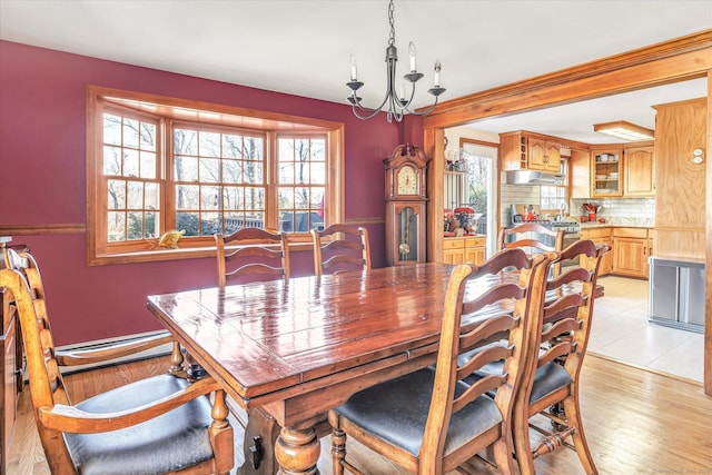 dining space with an inviting chandelier, a baseboard heating unit, light hardwood / wood-style floors, and a healthy amount of sunlight