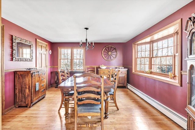 dining space with a baseboard heating unit, an inviting chandelier, and light hardwood / wood-style floors