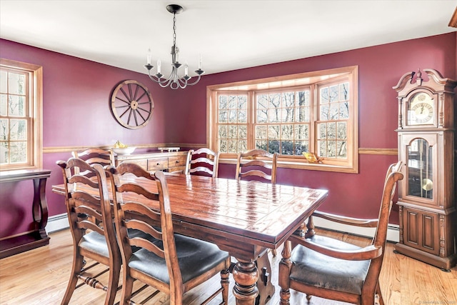 dining room featuring a baseboard radiator, an inviting chandelier, and light wood-type flooring