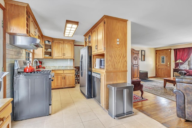 kitchen with stainless steel appliances, light tile patterned flooring, and decorative backsplash