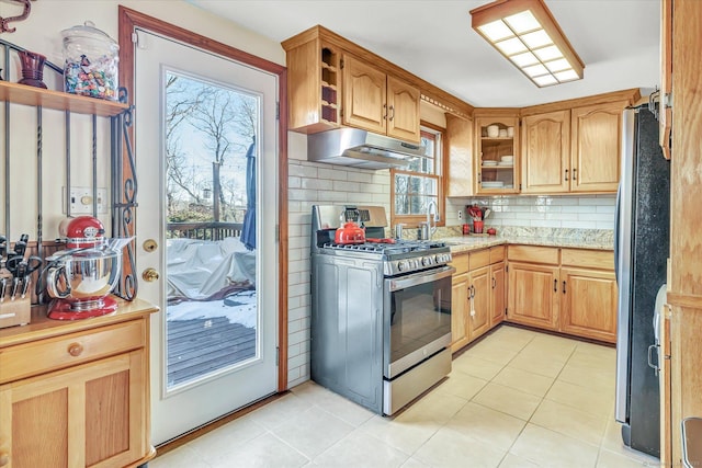 kitchen featuring backsplash, stainless steel appliances, a healthy amount of sunlight, and light tile patterned flooring