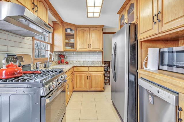 kitchen with tasteful backsplash, extractor fan, light tile patterned flooring, and appliances with stainless steel finishes