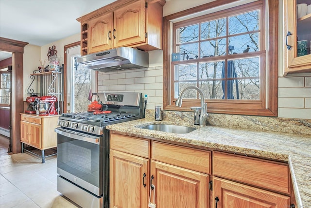 kitchen with stainless steel range with gas cooktop, sink, decorative backsplash, light tile patterned floors, and light stone countertops