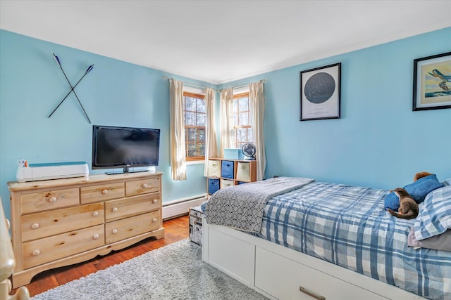 bedroom with hardwood / wood-style floors and a baseboard radiator