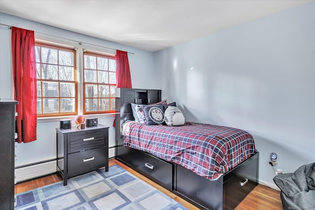 bedroom with baseboard heating and light hardwood / wood-style flooring