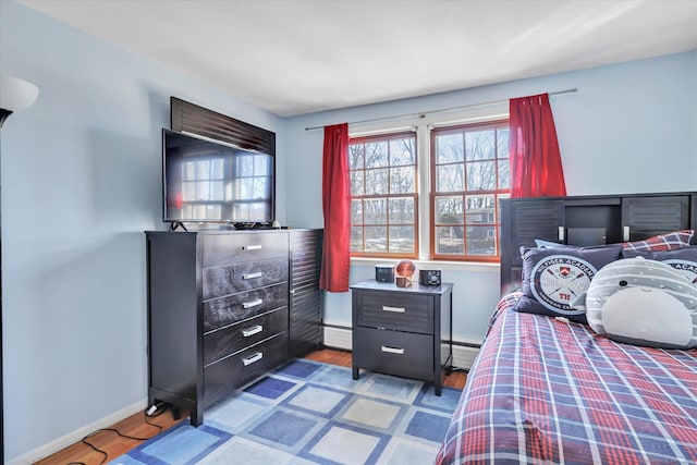 bedroom with light hardwood / wood-style floors and baseboard heating