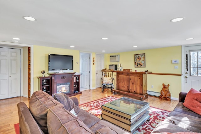 living room with an AC wall unit, baseboard heating, and light hardwood / wood-style floors