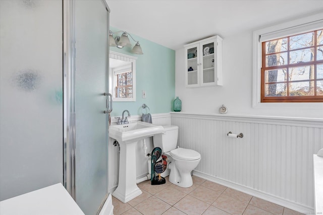 bathroom featuring tile patterned floors, toilet, and a shower with door