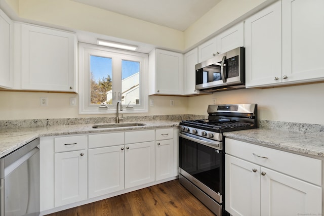 kitchen featuring sink, appliances with stainless steel finishes, dark hardwood / wood-style floors, light stone countertops, and white cabinets