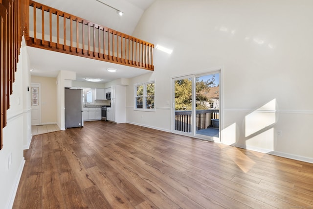 unfurnished living room featuring a high ceiling and light hardwood / wood-style floors