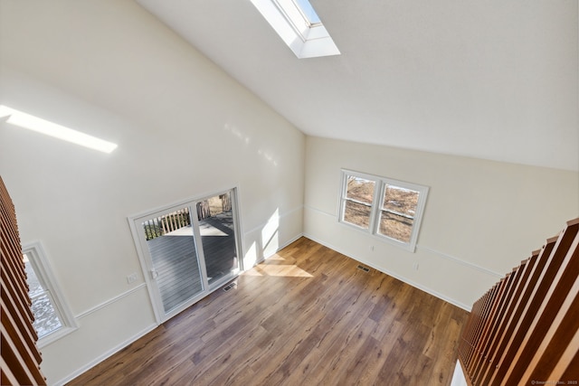 unfurnished living room featuring hardwood / wood-style floors and lofted ceiling with skylight