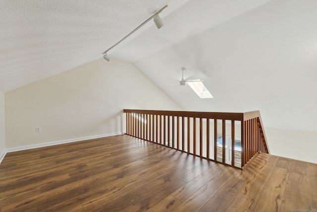 additional living space featuring lofted ceiling with skylight, dark wood-type flooring, a textured ceiling, and ceiling fan