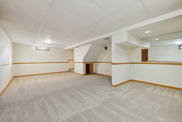 basement featuring a paneled ceiling and light colored carpet