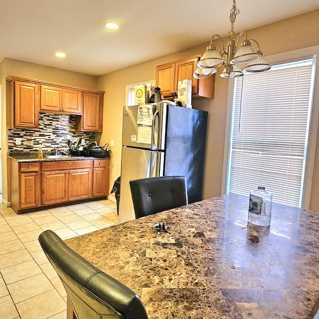 kitchen with pendant lighting, stainless steel fridge, an inviting chandelier, backsplash, and light tile patterned flooring