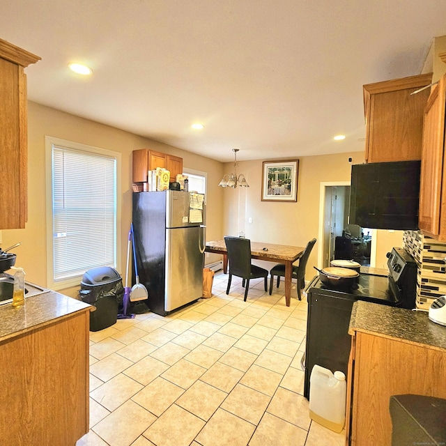 kitchen with black electric range oven, sink, decorative light fixtures, light tile patterned floors, and stainless steel fridge