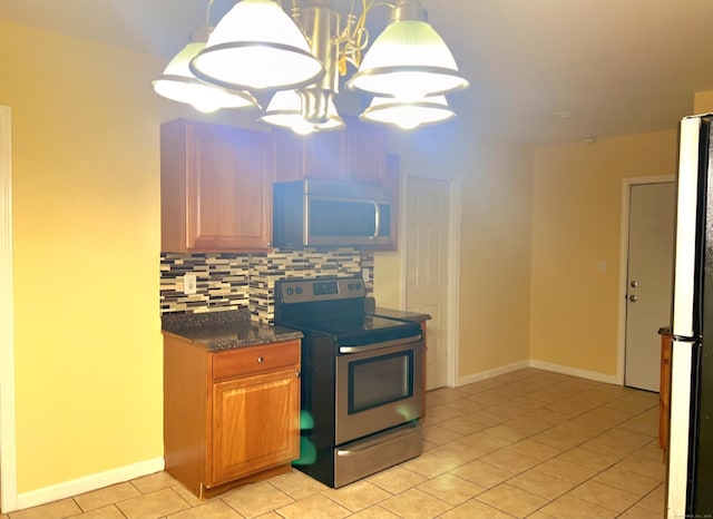 kitchen featuring pendant lighting, light tile patterned floors, refrigerator, tasteful backsplash, and stainless steel range with electric cooktop