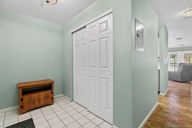 hall with electric panel and light tile patterned floors