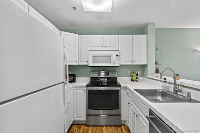 kitchen with hardwood / wood-style flooring, appliances with stainless steel finishes, sink, and white cabinets