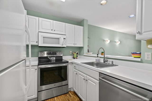 kitchen with appliances with stainless steel finishes, sink, dark wood-type flooring, and white cabinets