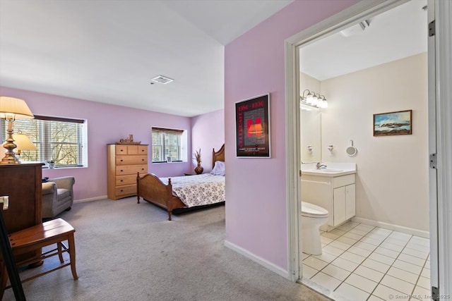 carpeted bedroom with connected bathroom and sink