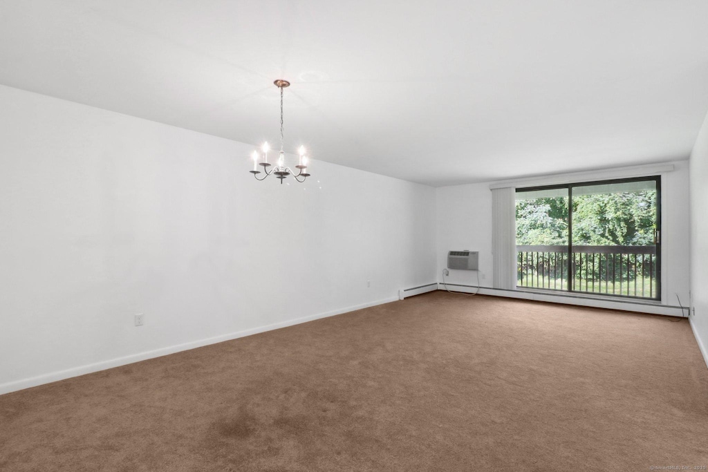 carpeted spare room featuring a baseboard radiator, a wall unit AC, and a chandelier