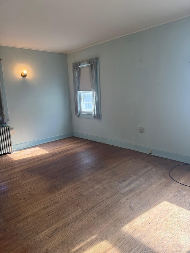 empty room featuring dark hardwood / wood-style floors, cooling unit, and radiator