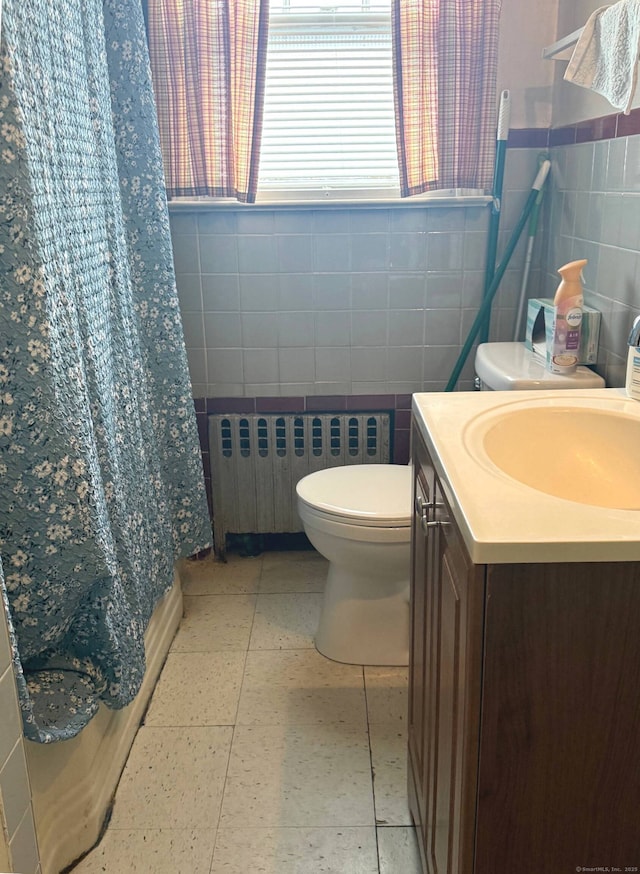 bathroom featuring radiator heating unit, tile walls, vanity, toilet, and tile patterned floors