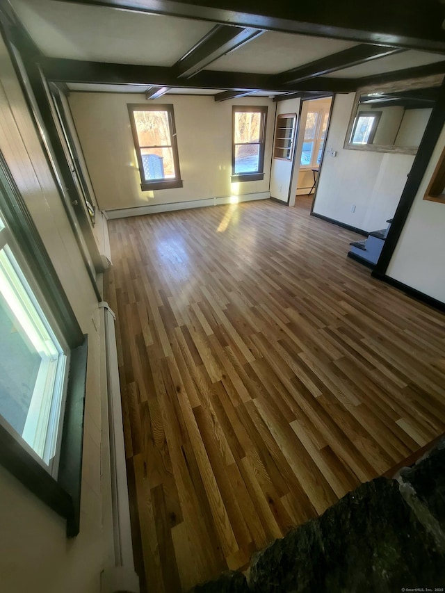 unfurnished living room featuring beam ceiling, baseboards, and wood finished floors