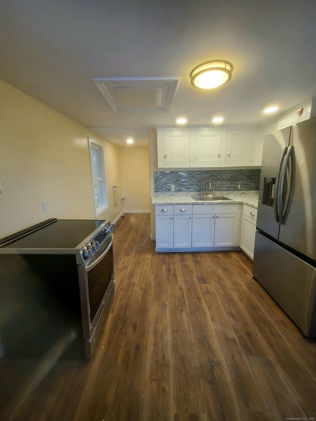 kitchen featuring stainless steel appliances, dark wood-style flooring, a sink, white cabinetry, and decorative backsplash