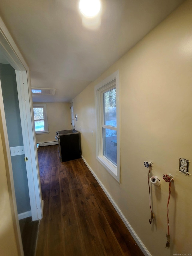 hall with a baseboard heating unit, dark wood-style flooring, and baseboards