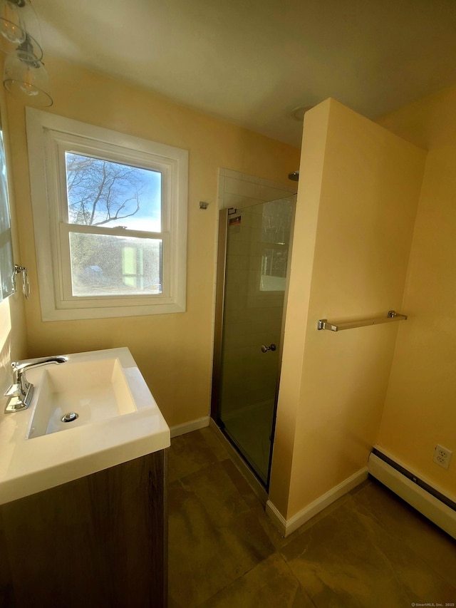 bathroom with a shower stall, a baseboard heating unit, baseboards, and vanity