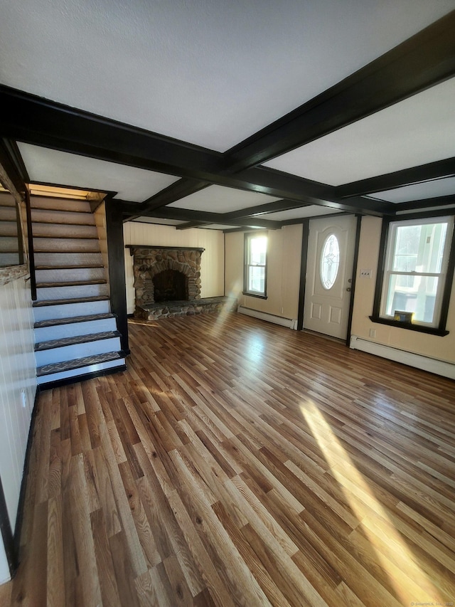 unfurnished living room featuring stairs, baseboard heating, wood finished floors, and beam ceiling