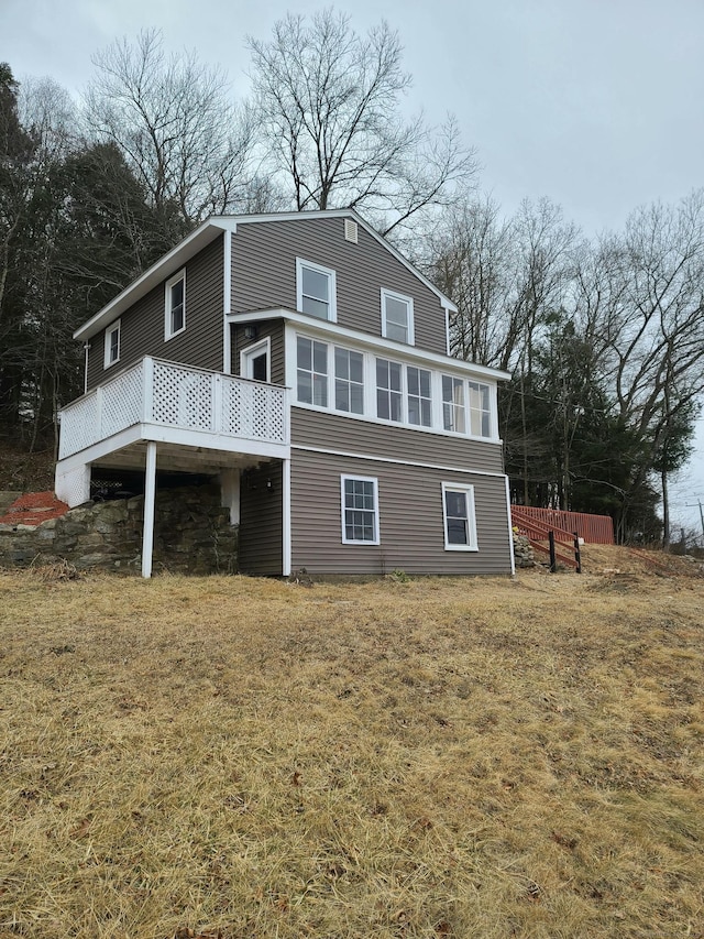 back of house with a yard, a wooden deck, and a sunroom