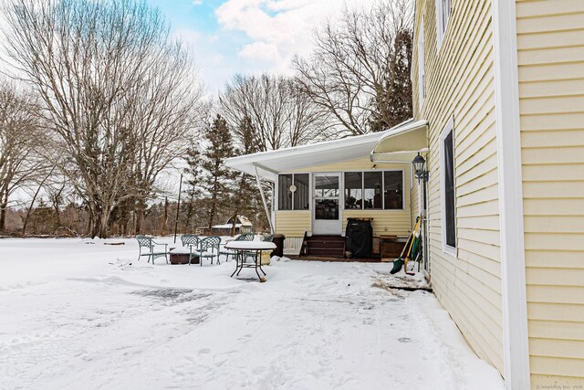 yard covered in snow with a sunroom