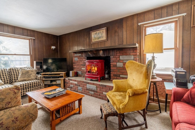 living room featuring a wood stove, light carpet, and wooden walls