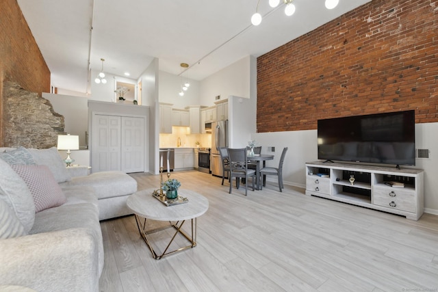 living room featuring a high ceiling, sink, and light hardwood / wood-style flooring