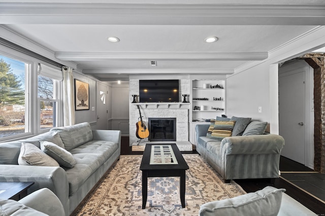 living room with beamed ceiling, ornamental molding, a fireplace, and built in shelves