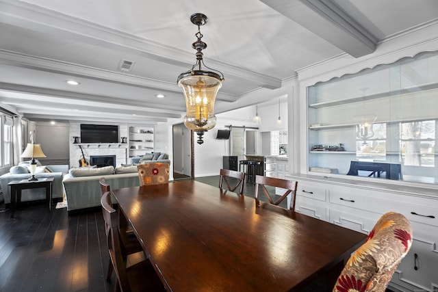 dining space featuring hardwood / wood-style flooring, ornamental molding, a barn door, beam ceiling, and built in shelves