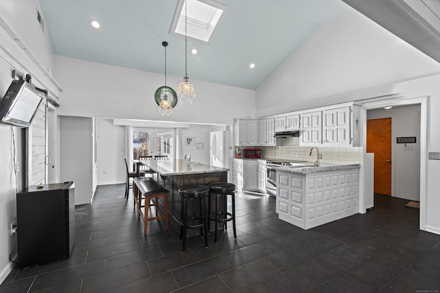 dining space with high vaulted ceiling, a skylight, sink, a barn door, and french doors