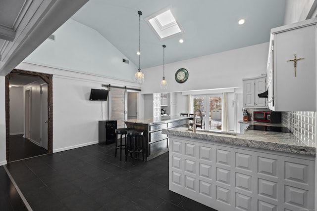 kitchen featuring white cabinetry, decorative light fixtures, light stone counters, and a kitchen island