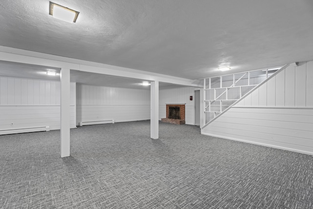 basement with a baseboard radiator, carpet flooring, a fireplace, and a textured ceiling