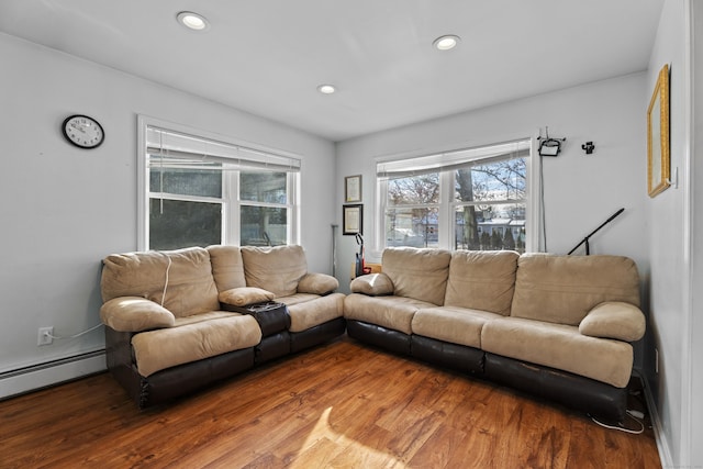 living room with a baseboard heating unit and wood-type flooring