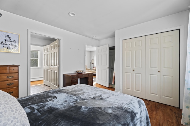 bedroom featuring ensuite bath, wood-type flooring, a closet, and baseboard heating