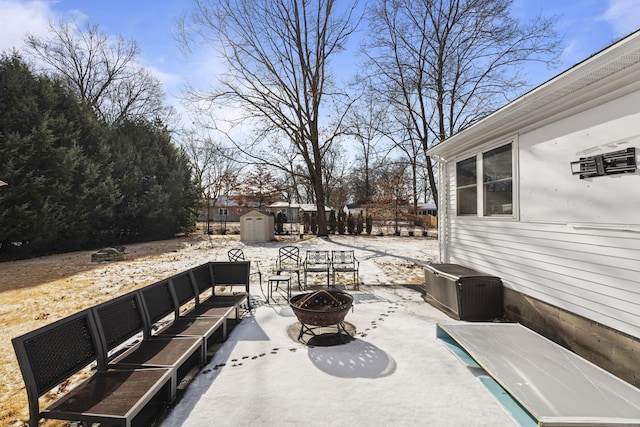 snow covered patio featuring a storage unit and a fire pit