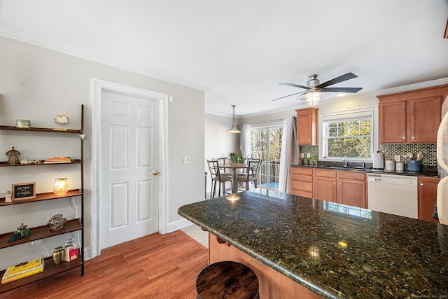 kitchen with pendant lighting, crown molding, white dishwasher, tasteful backsplash, and light hardwood / wood-style floors