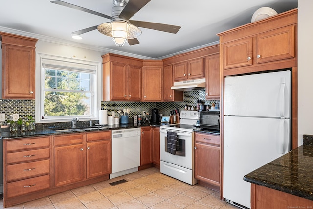 kitchen featuring tasteful backsplash, sink, dark stone counters, light tile patterned floors, and white appliances