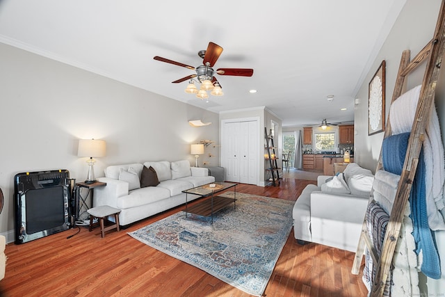 living room featuring hardwood / wood-style flooring, ceiling fan, and crown molding